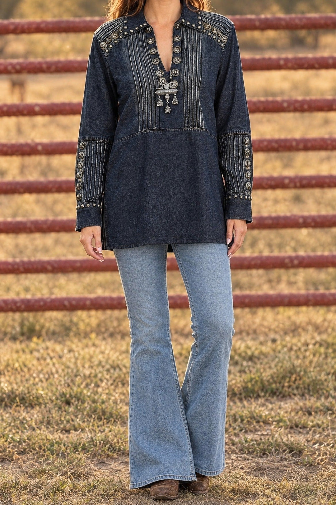 Silver concho studded denim tunic with flare jeans by a ranch fence