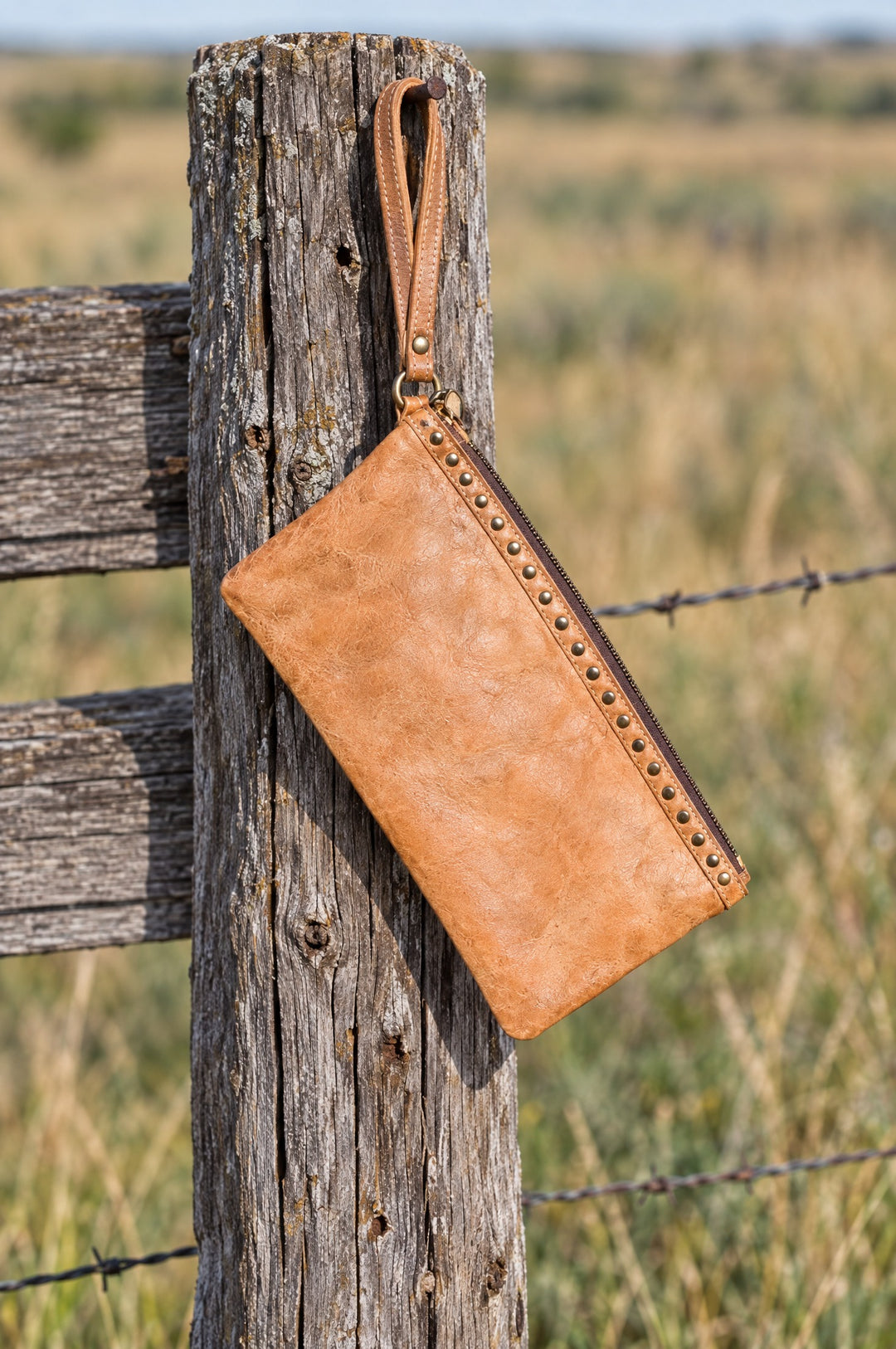 Tan leather wristlet hanging on a fence