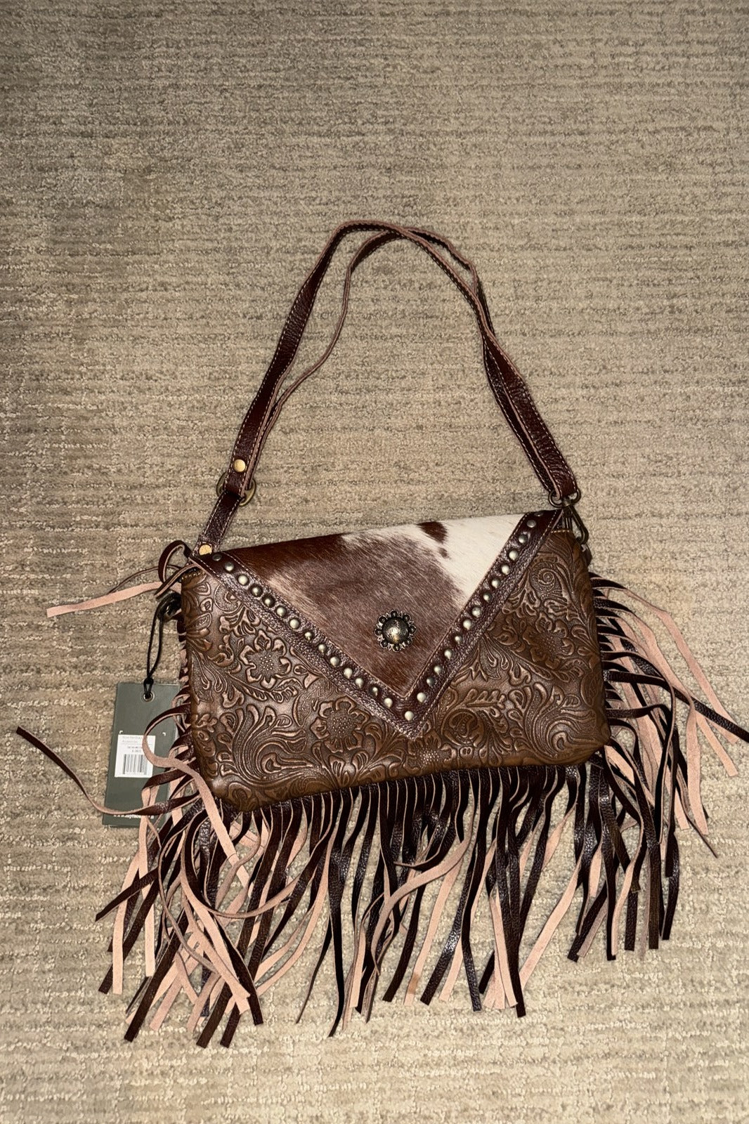 Dusky fringe handbag with brown and white cowhide flap, studs, concho and shoulder strap