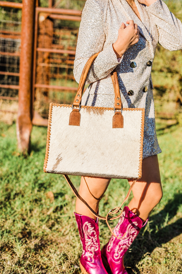 Hair on cowhide tote carried with pink boots