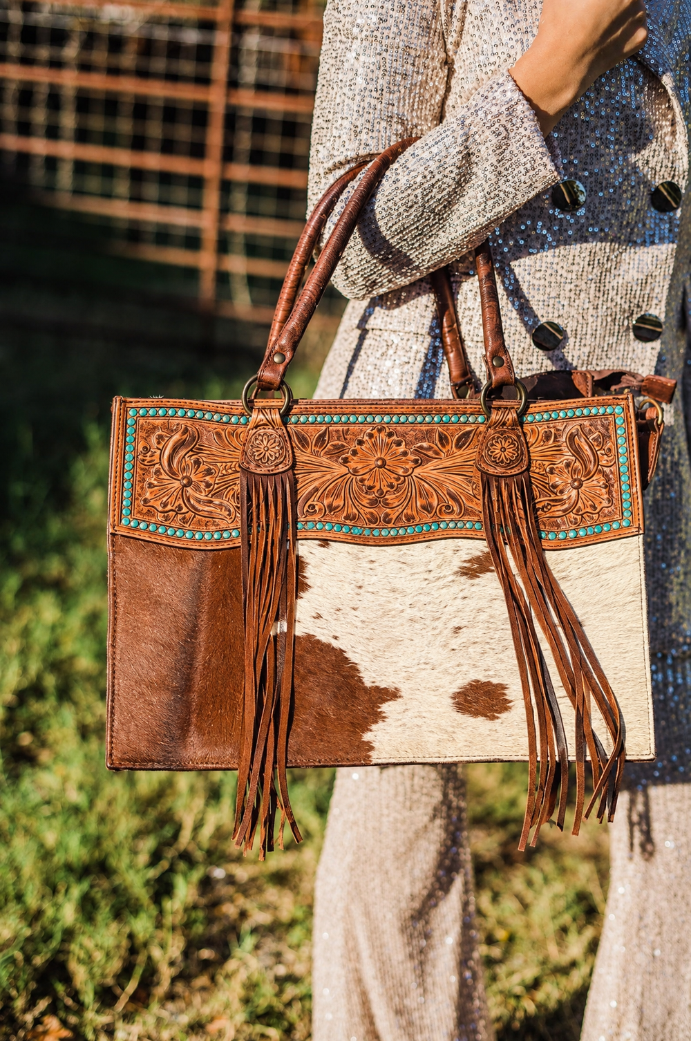 Tooled leather cowhide tote with turquoise lacing on model
