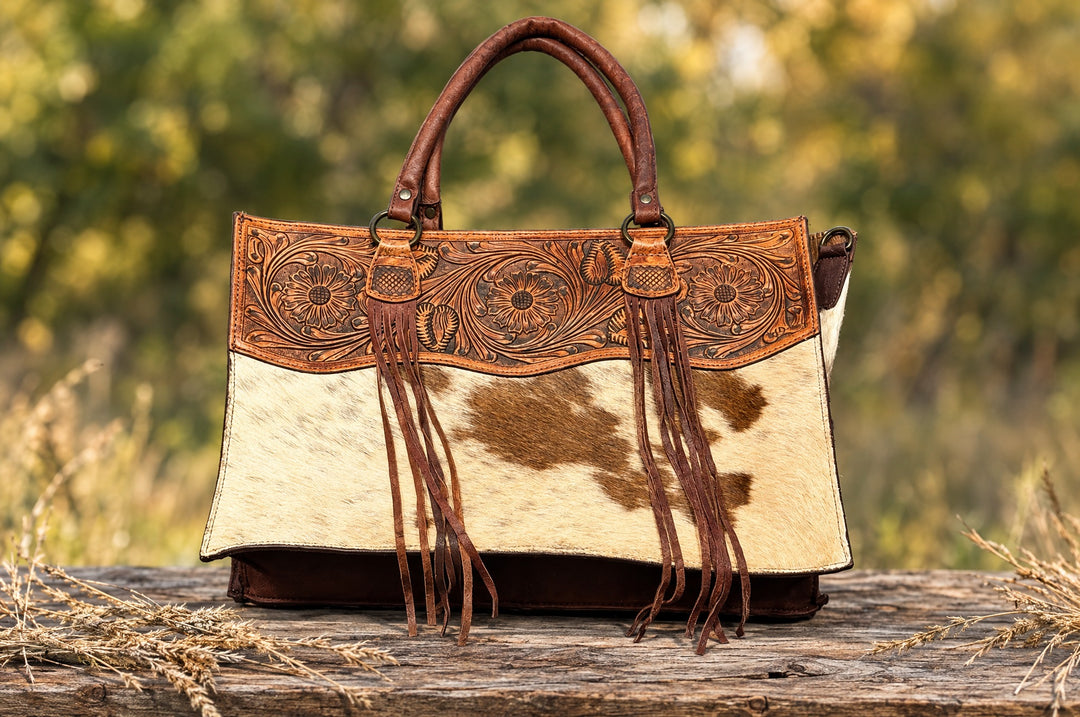 Pack Up tooled cowhide tote on a wood table outdoors
