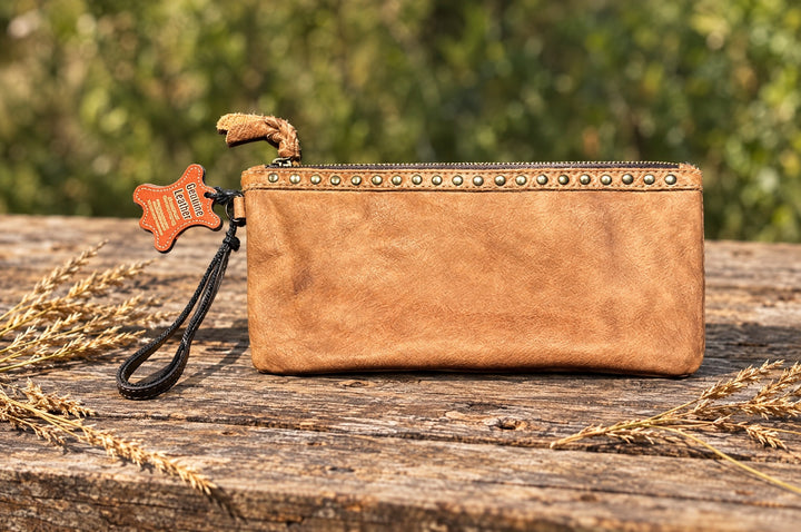 Tan leather zip pouch on a weathered wood table