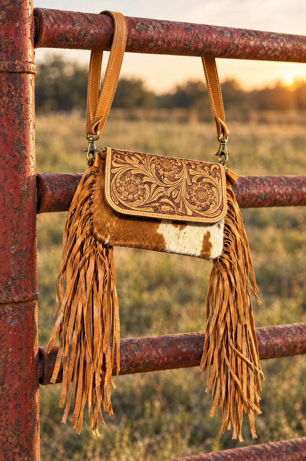 Tooled leather fringe crossbody hanging on a ranch gate